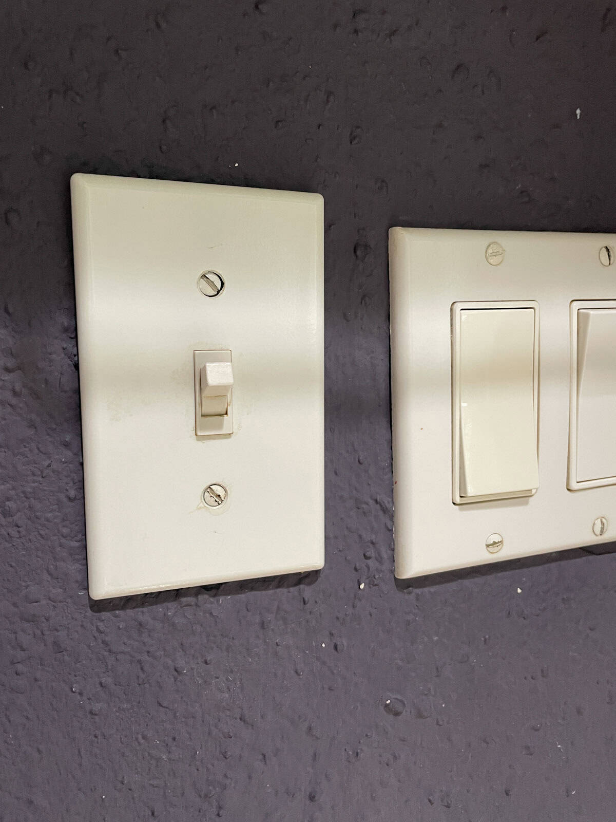Close-up of a light switch on a textured wall painted with James Alexander Natural Paint after one year, showing durable coverage around high-touch areas.