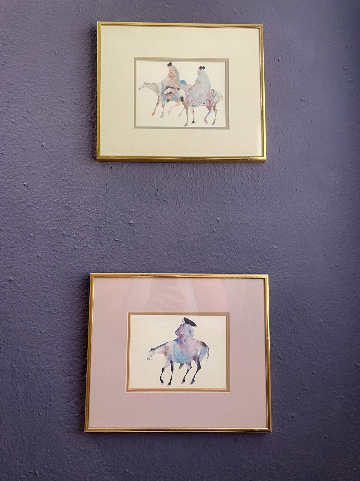 Two gold-framed watercolor horse prints displayed on a textured bathroom wall painted with James Alexander Natural Paint one year after application.