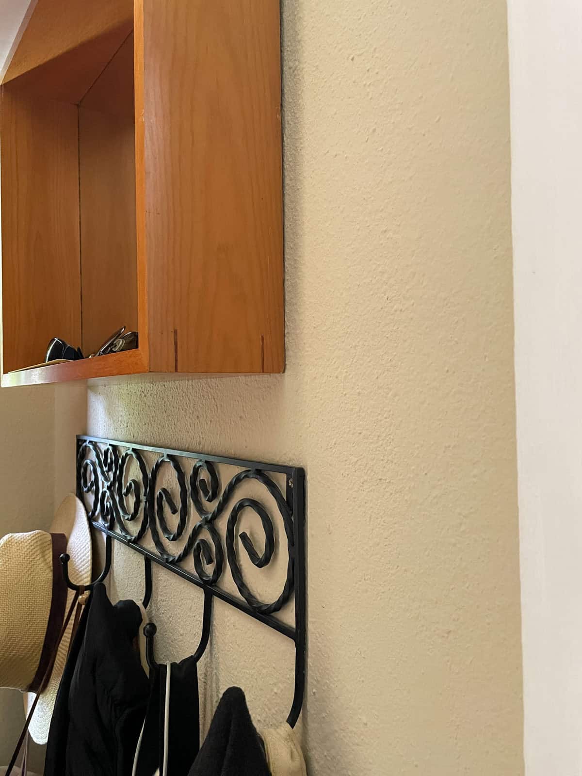 Textured hallway wall painted with James Alexander Natural Paint beside a wood cabinet and decorative coat rack after one year.