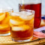 Rooibos iced tea with loose leaf tea served over ice with a mason jar of brewed tea in the background.