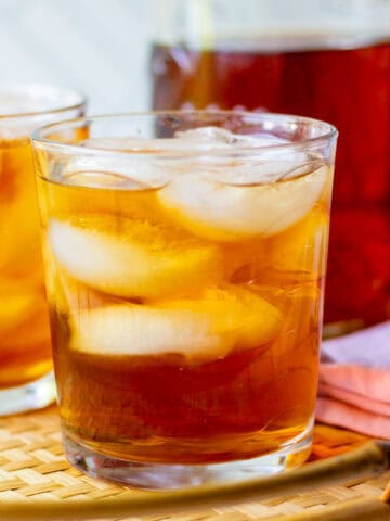 Rooibos iced tea with loose leaf tea served over ice with a mason jar of brewed tea in the background.
