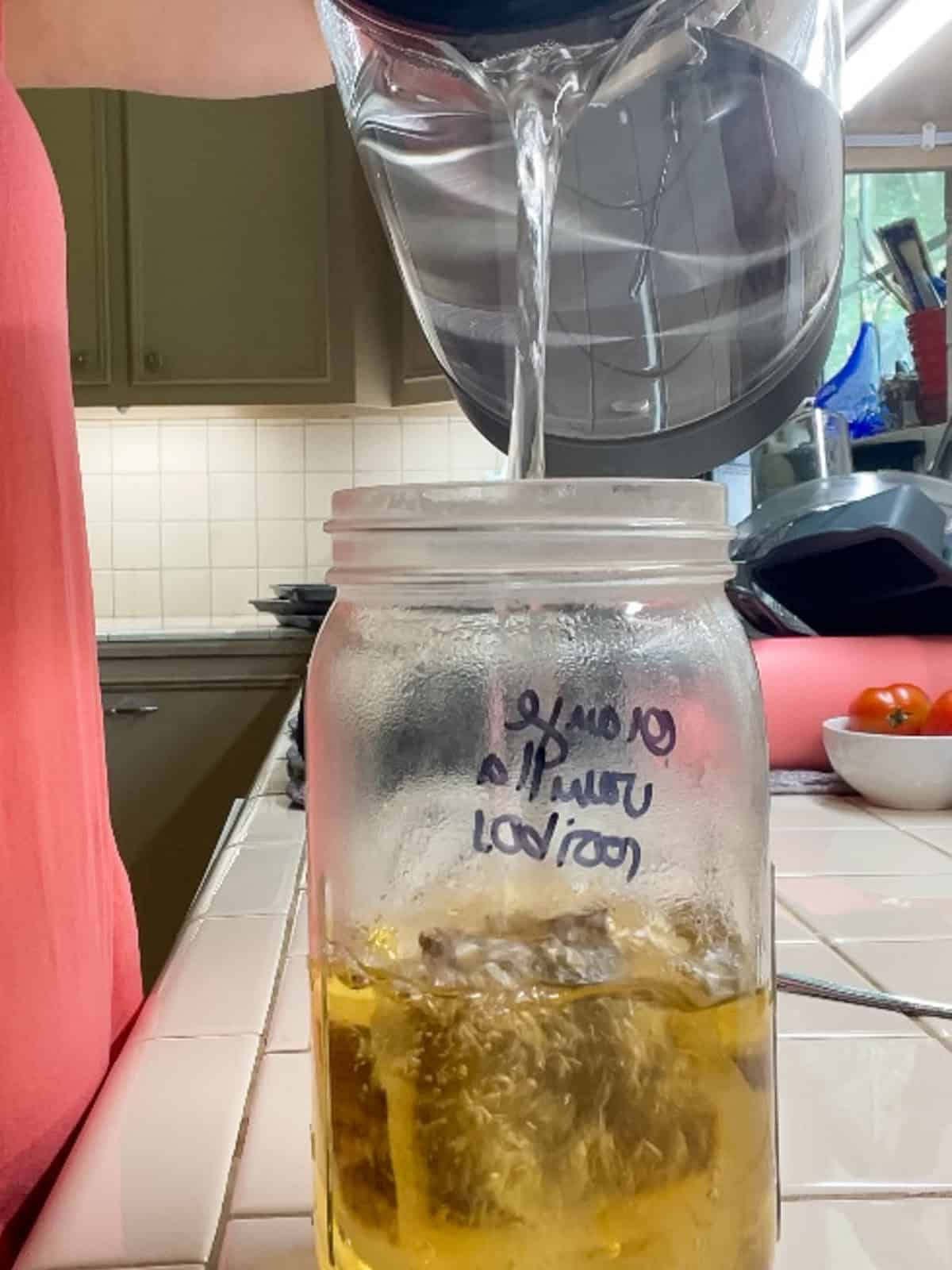 Hot water being poured over rooibos tea bags in a mason jar to brew rooibos iced tea from scratch.