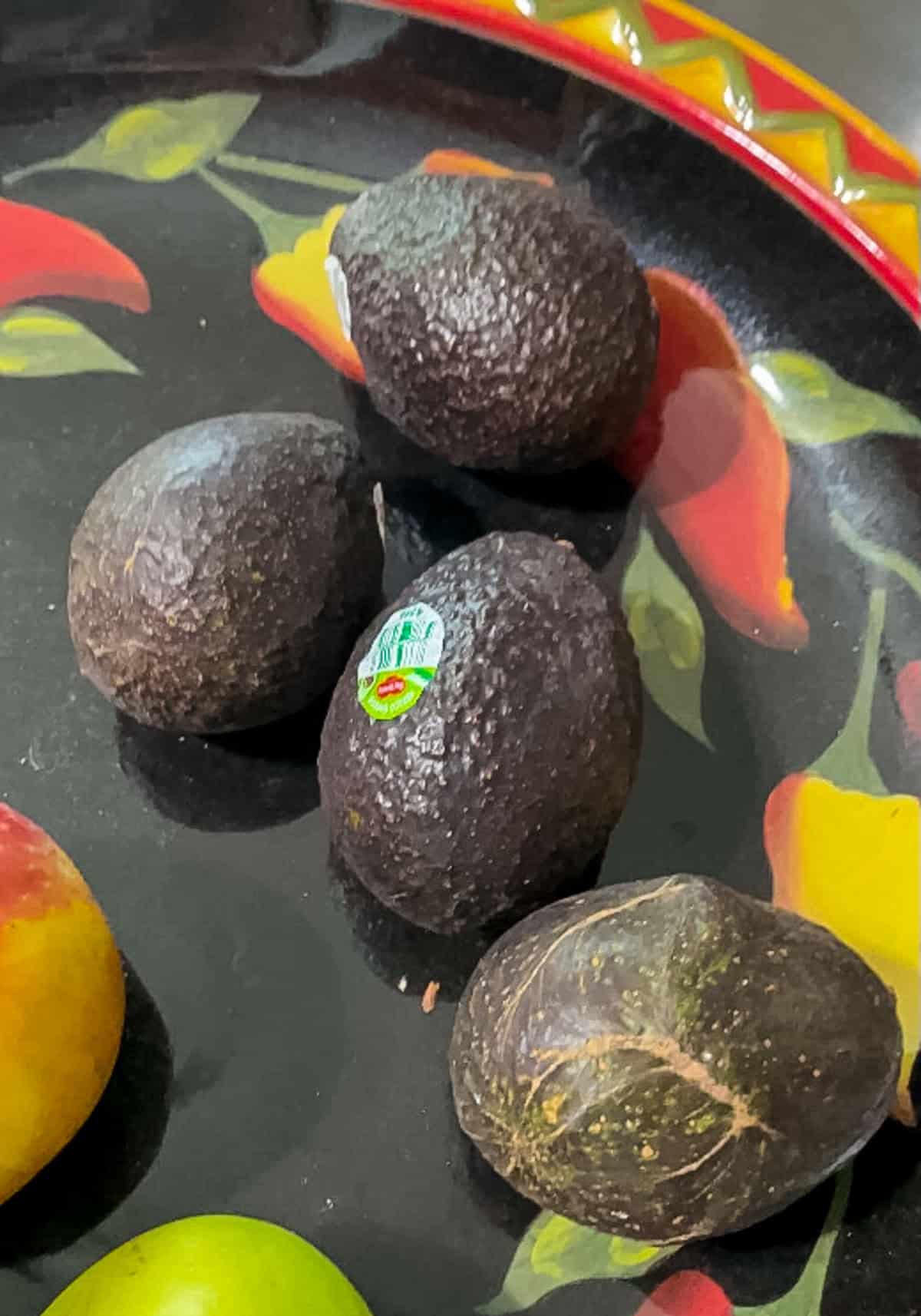 Ripe Hass avocados on a fruit bowl, ready to be moved to the refrigerator to extend freshness and shelf life.