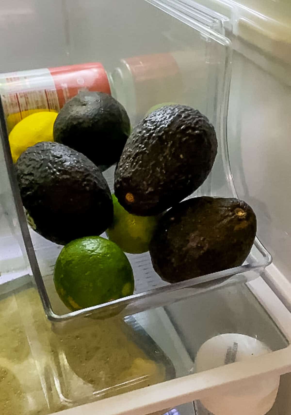 Ripe avocados stored in the refrigerator crisper drawer using an avocado storage hack to keep them fresh for weeks.